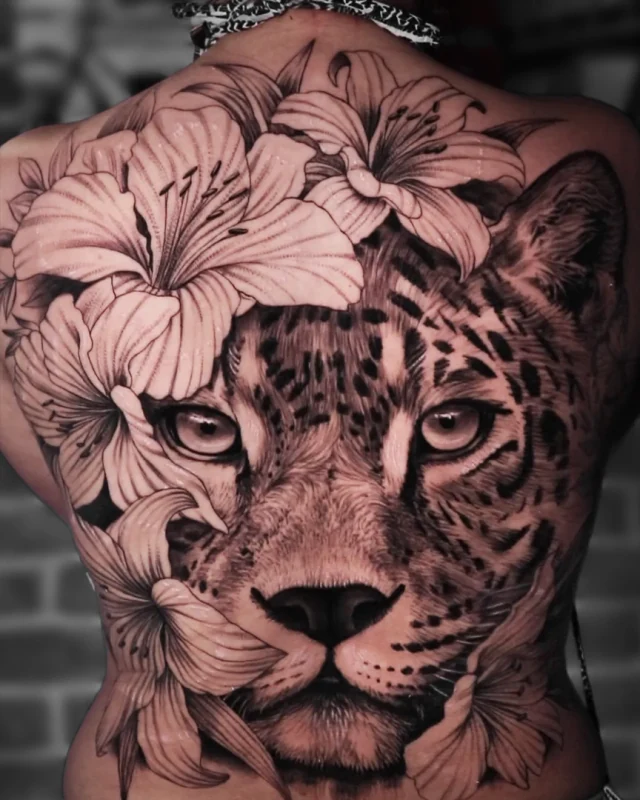 Tatuagem realista de onça com flores nas costas, por Lucas Franca